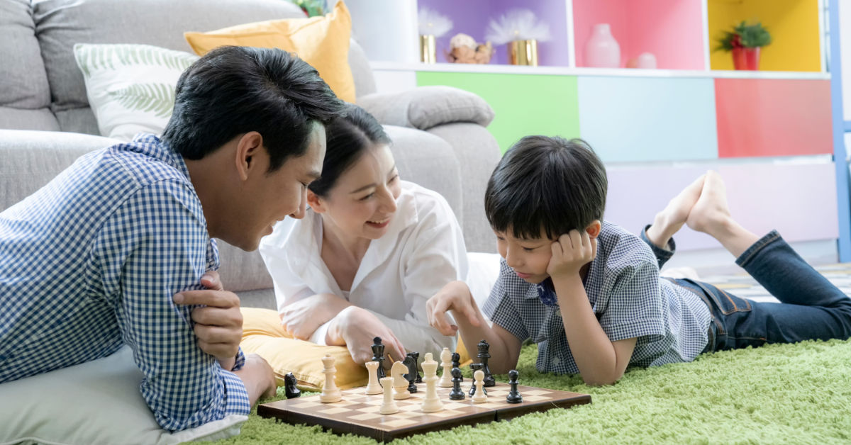 Child playing chess with parent on floor