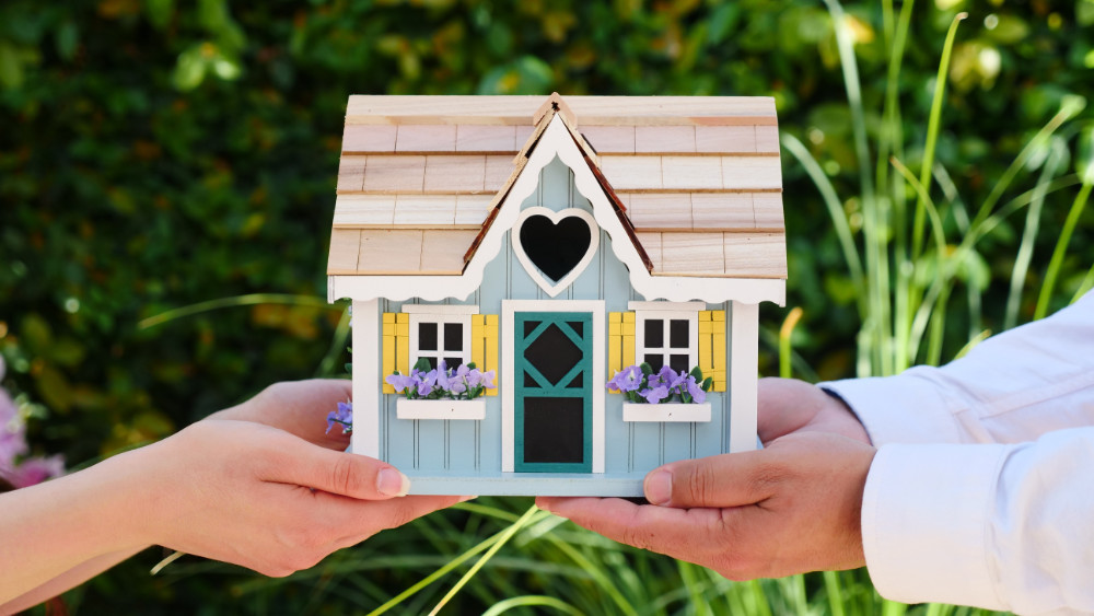 Couple holding wooden home model in hands. Buying a new home.